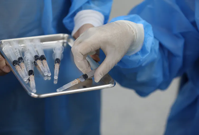 A medic holds a tray of syringes filled with COVID vaccine.