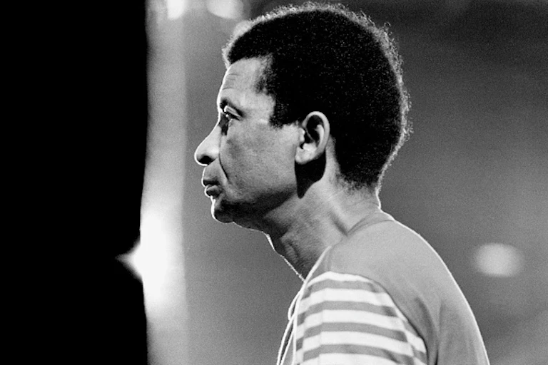 A black and white photo of an African man with natural hair in profile, looking straight ahead.