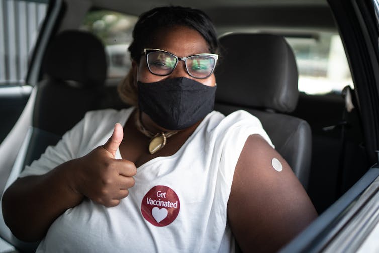 A woman gives a thumbs-up after getting a COVID-19 vaccine.