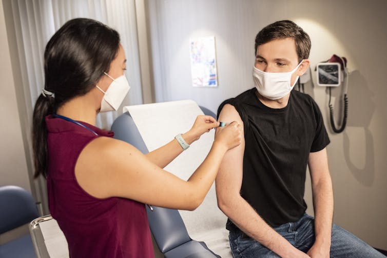 A health-care worker puts a band-aid on a young person's arm after a vaccination.