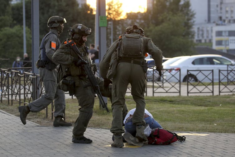 Police officers kick a demonstrator in Minsk.