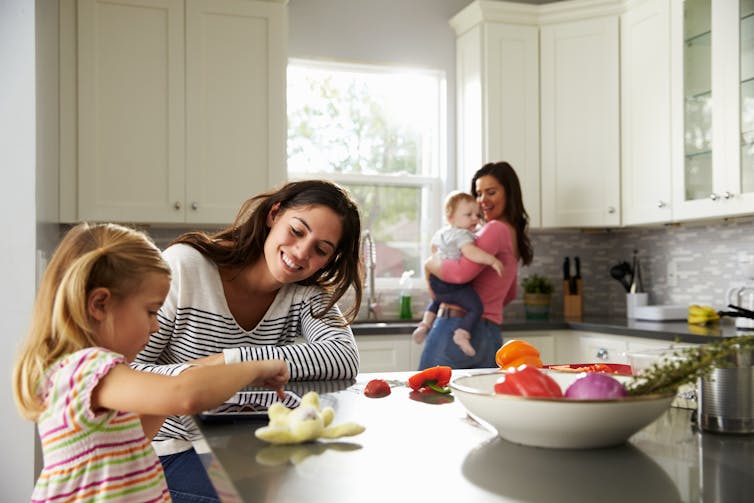 Lesbian couple with two young children in the kitchen.