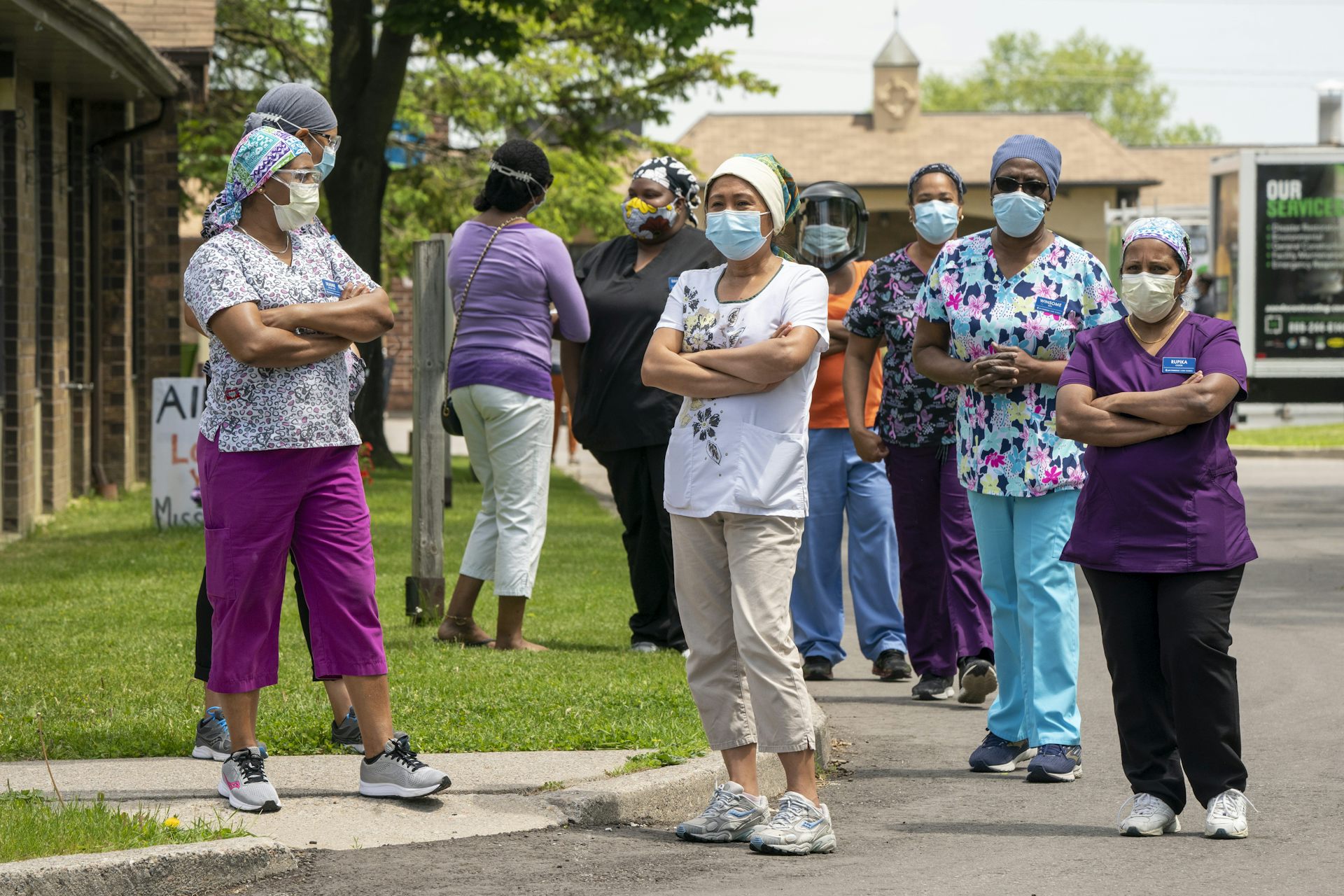 Workers wearing masks stand in a group outside a long-term care home.