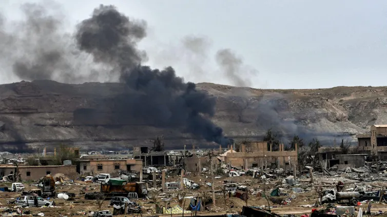 Smoke rises from buildings in the Islamic State’s former caliphate in Syria’s eastern Deir Ezzor province near the Iraqi border, a day after the group was declared defeated by the Syrian Democratic Forces (SDF)