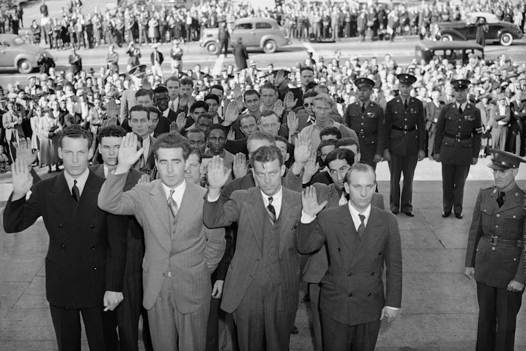 Men in suits stand in formation and raise their right hands