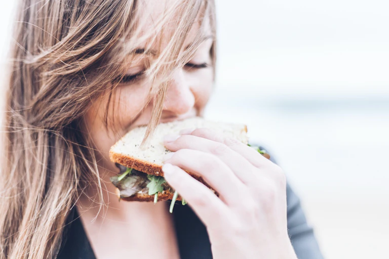 A woman takes a bite of a sandwich.