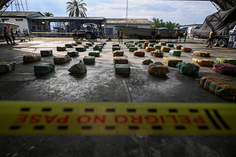 Warehouse with rows of plastic packages lined up and a caution tape running across foreground