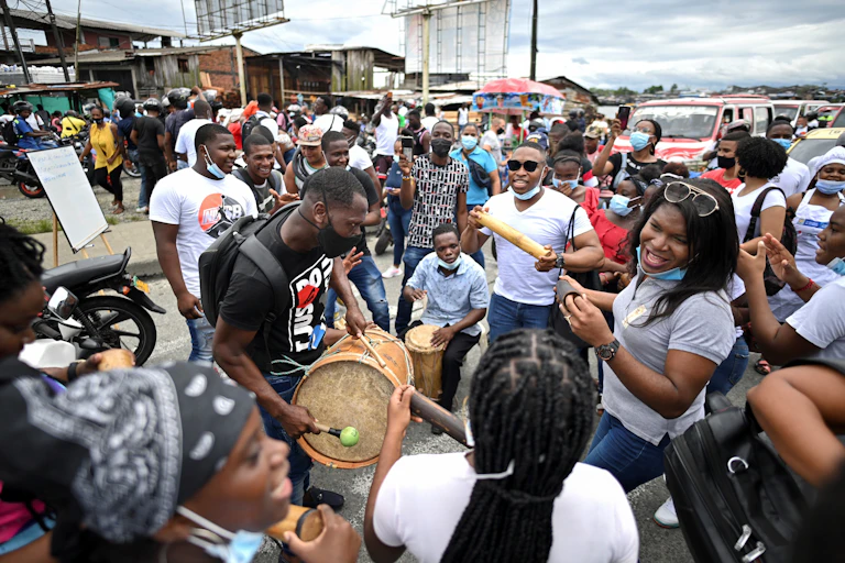 Black Colombians, most in surgical masks, sing and play music