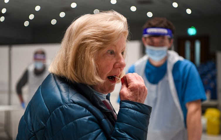 A woman inserting a swab into her mouth.