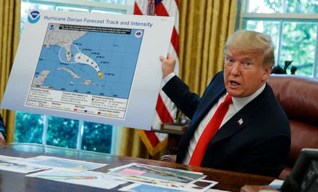Donald Trump, in the Oval Office, holding up a forecast of a hurricane track that someone had drawn on to extend the track past the official forecast.