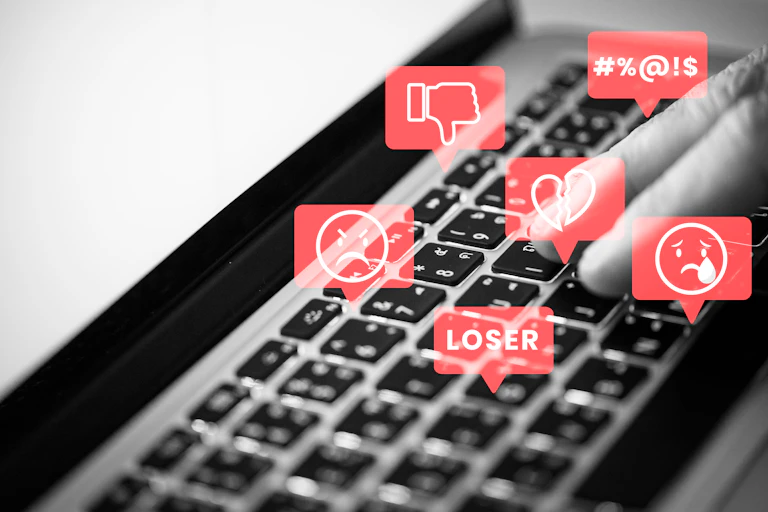 Icons showing thumbs down, expetives and frowning emoji floating over a keyboard