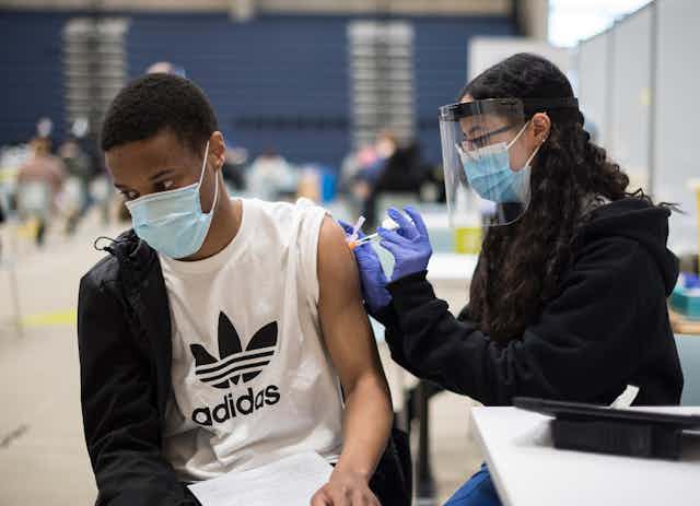A young man in a mask is vaccinated