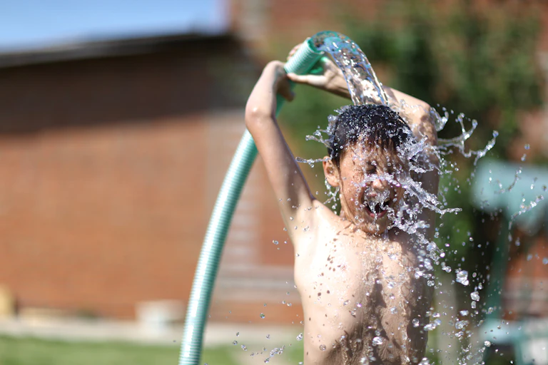 Child cooling off under garden hose