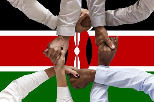 People joining hands with a Kenyan flag in the background