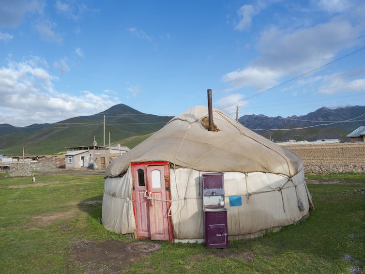 Choza circular construida con materiales básicos con un hermoso telón de fondo de montaña