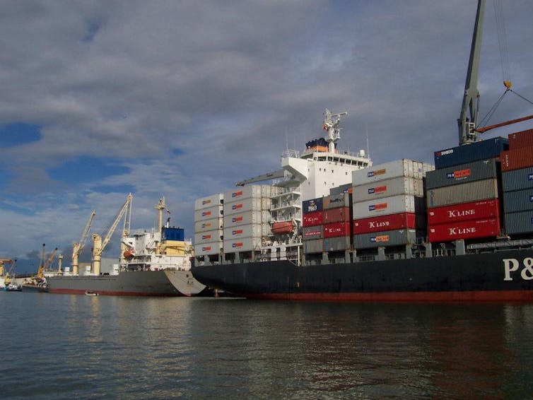 Large ships with stacked containers lined up in the water