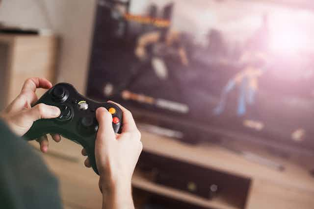 A youngster plays with a video game controller in front of a screen