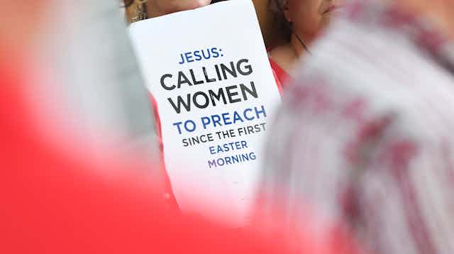 A poster saying 'Jesus: Calling women to preach since the first Easter morning,' is held up by protestors outside a Southern Baptist Convention annual meeting in 2019.