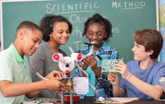 A group of middle school students work together on a robotics project.