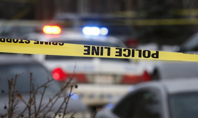 Yellow police tape in front of a police cruiser.