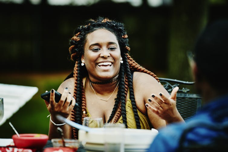Laughing woman of large body size, in discussion with friends during backyard party Thomas Barwick/Stone via Getty