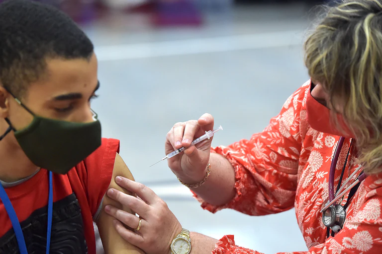 School nurse gives a high school student a COVID-19 vaccine