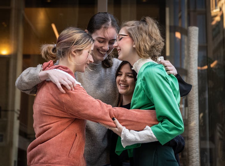 Four teenagers hugging outside the court