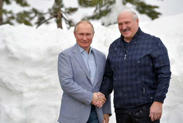 Russian President Vladimir Putin (L) shakes hands with Belarus President Alexander Lukashenko against a snowy background in the Black sea resort of Sochi, Russia, February 2021.