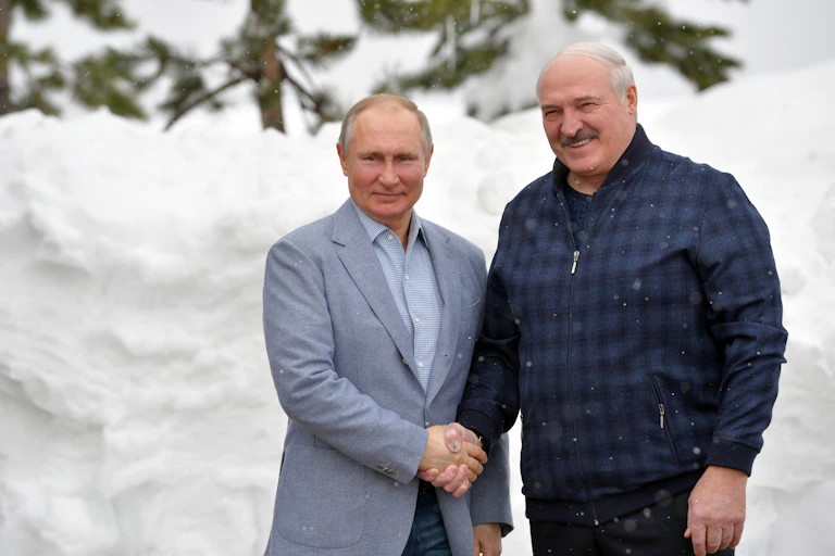 Russian President Vladimir Putin (L) shakes hands with Belarus President Alexander Lukashenko against a snowy background in the Black sea resort of Sochi, Russia, February 2021.