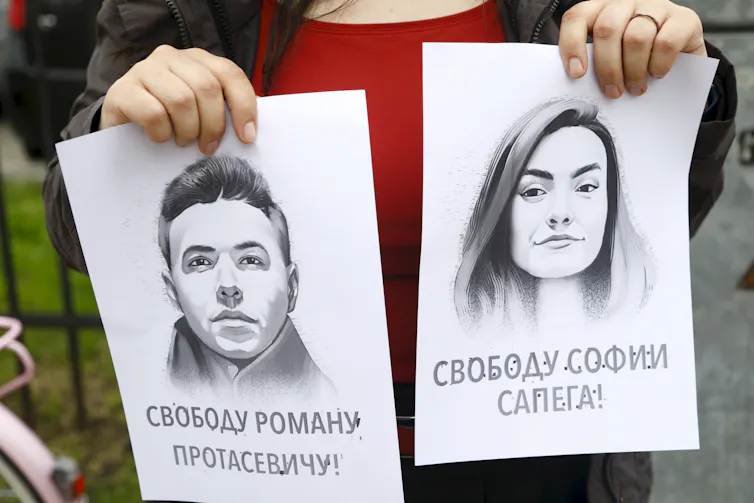 A woman holds portraits of journalist Roman Protasevich and his girlfriend Sofia Sapega.