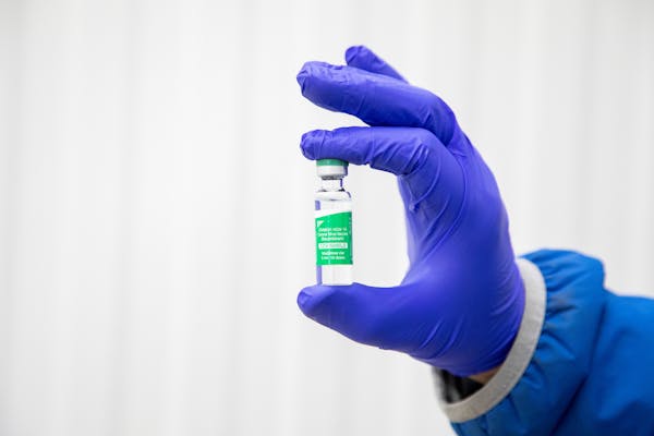 Hand in a purple glove holding a vial of vaccine