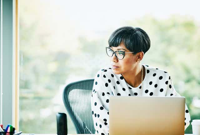 woman at laptop pensively looks off into distance