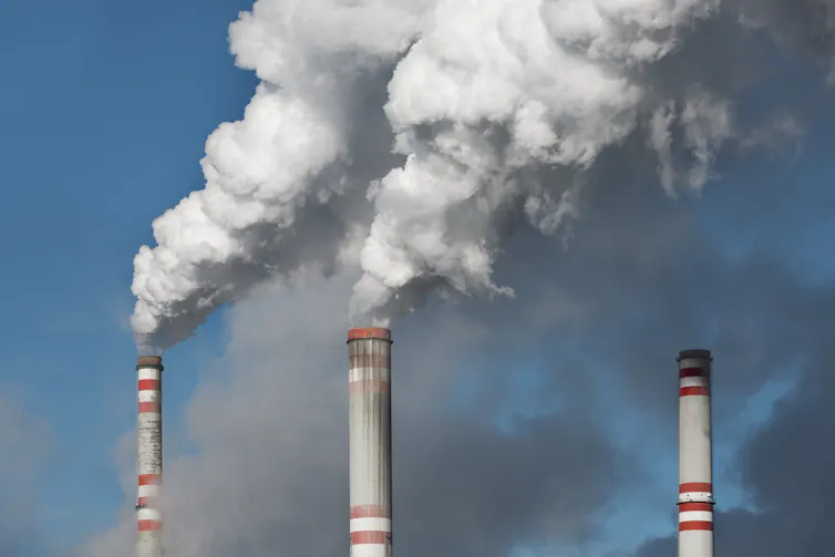 Three smoke stacks belching white smoke from a coal-fired power plant.