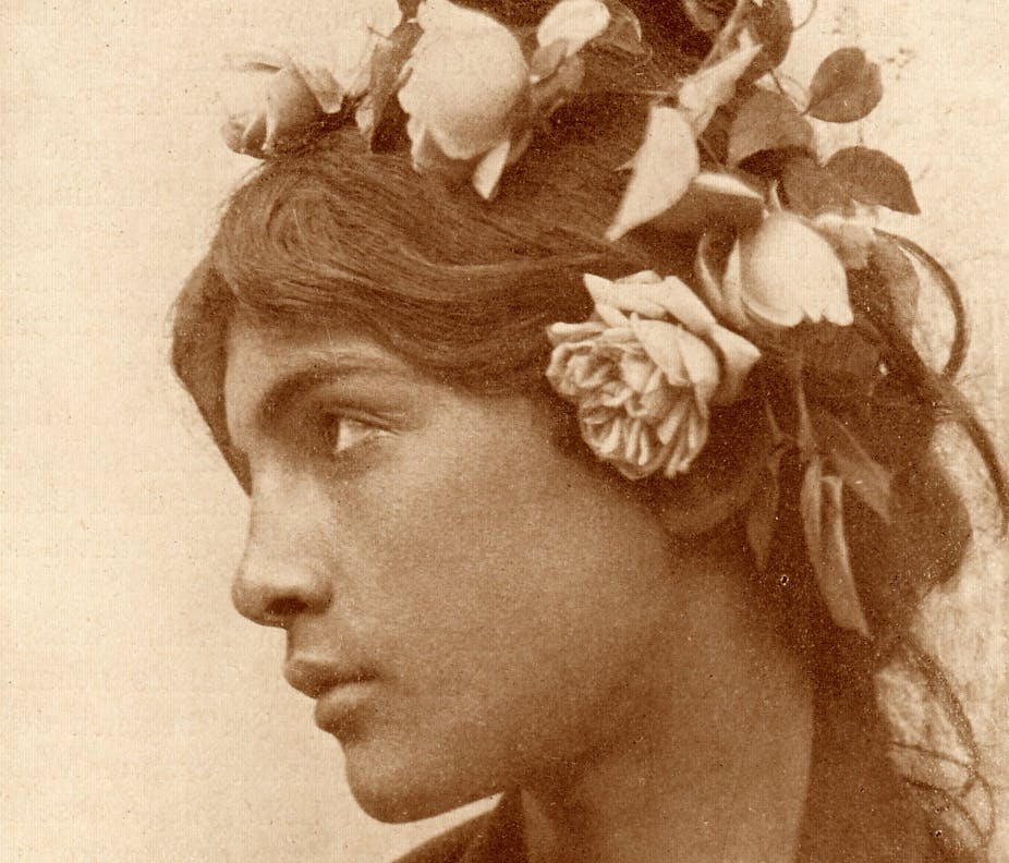 A boy wears a wig with flowers affixed to it.
