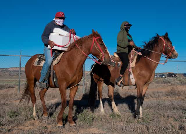 Native Americans of the Navajo Nation people, pick up supplies on horses at a food bank.