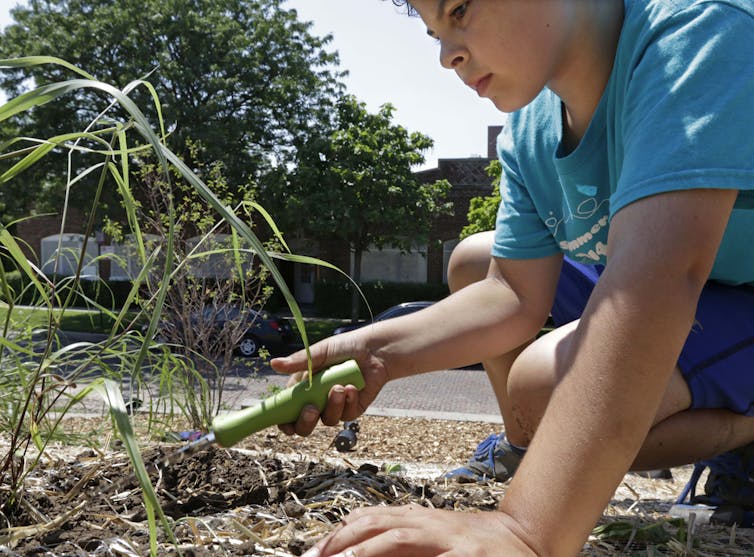 A child uses a spade to break up soil during a gardening exercise with the American Indian Center in Chicago.