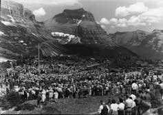 Crowds at a ceremony with mountains in the background.