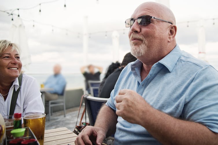 Man and friends enjoying a meal together on a restaurant terrace.