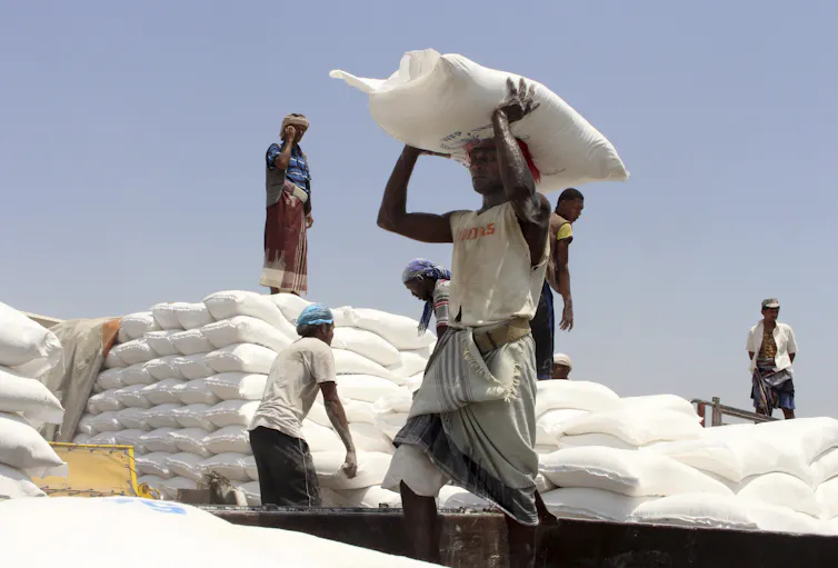 Yemeni men carrying sacks of food for distribution.