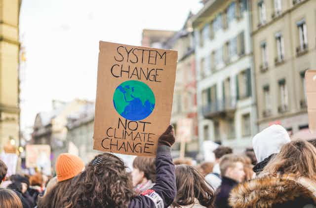 A person holding a sign saying "system change not climate change"