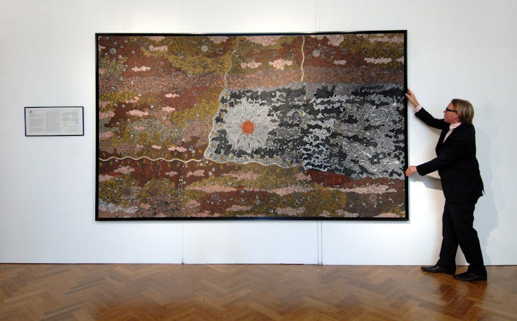 Man hangs large Indigenous painting