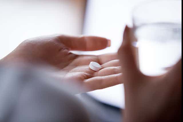 A hand holds a pill.