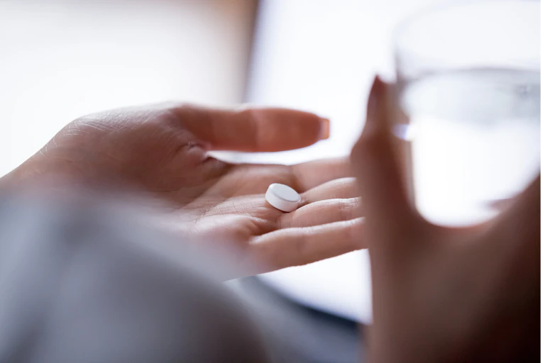 A hand holds a pill.