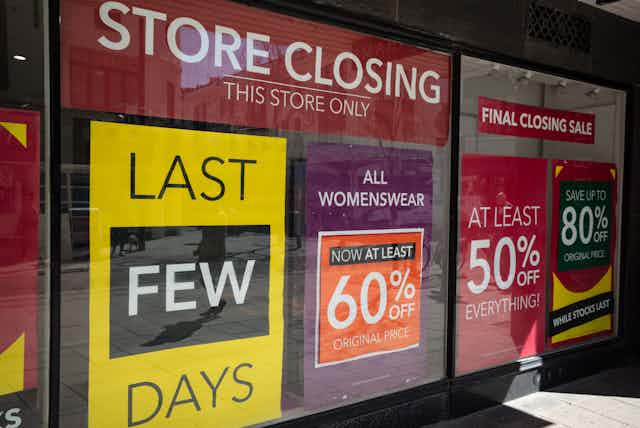 Department store window with posters indicating imminent closure.