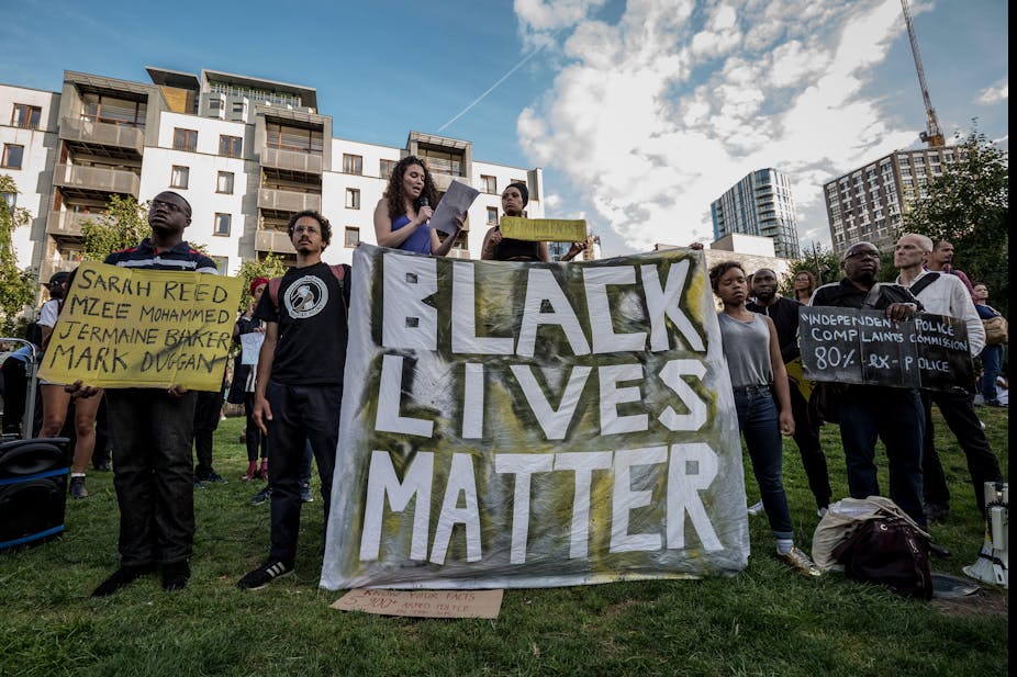 Protestors gathered together on a lawn holding up protest signs that say Black Lives Matter, Sarah Reed, Mzee Mohammed, Jermaine Baker, Mark Duggan and Independent Police Complaints Commission 80 per cent ex-police