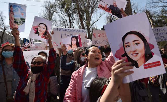 A crowd of wome hold up signs and pictures