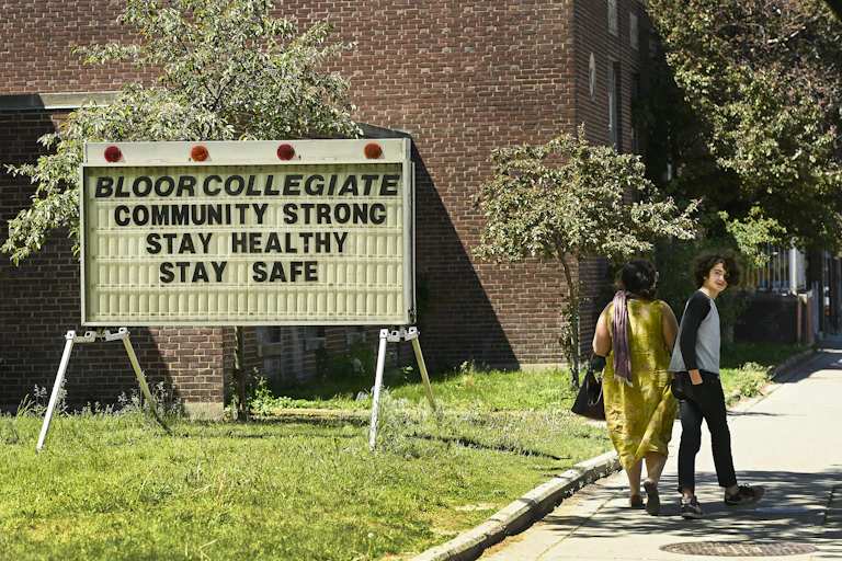 A teen turns while walking past school sign saying community strong stay healthy stay safe.