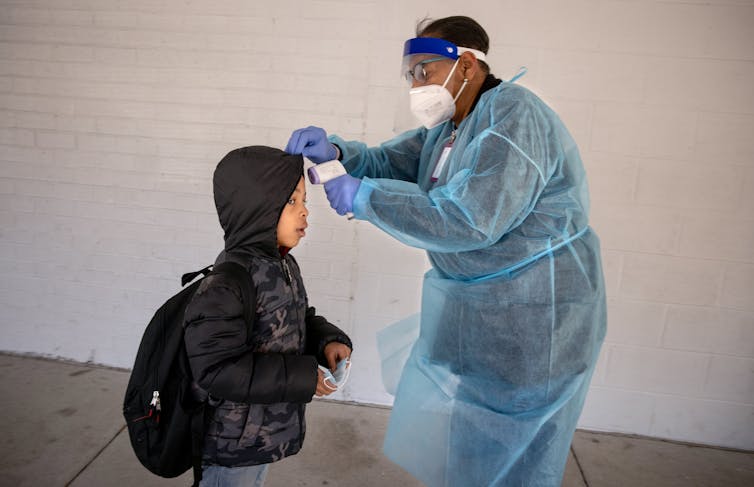 A school nurse takes a young student's temperature
