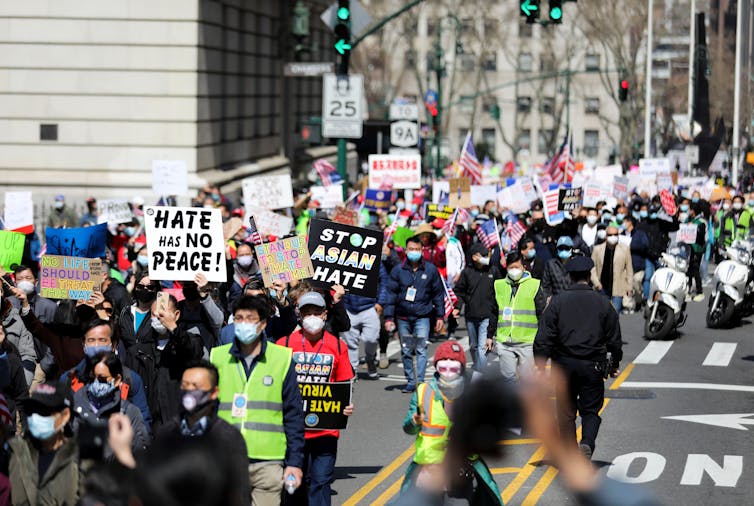 People march with signs that say 'Stop Asian Hate'