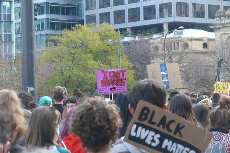 People holding large Aboriginal flag at a protest.